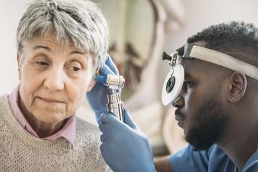 Close up of a older person assigned female at birth getting ears checked by doctor to look for vitamin E and tinnitus