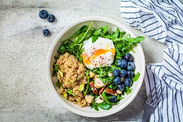 Quinoa salad with berries, poached egg and nuts, top view. Healthy food concept.