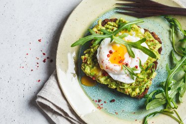 top view of avocado and poached egg toast on rye bread, as an example of foods with healthy fats