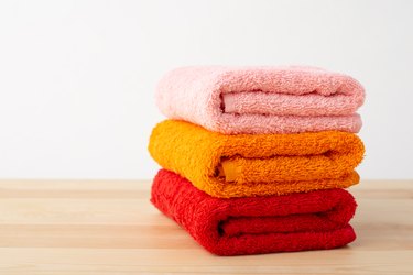 Three bath towels on wooden table.