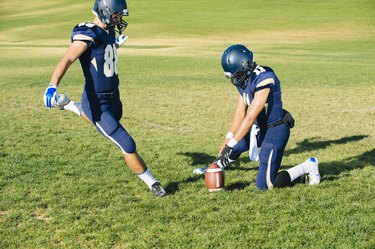 Teenage american footballers kick training on pitch