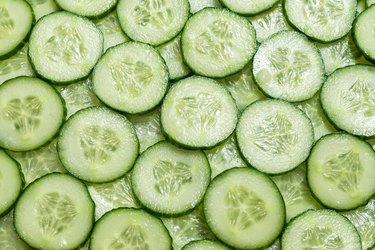 Fresh green slices of cucumber as background.