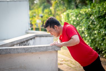 Man doing elevated push-ups against a wall in the park outdoor.