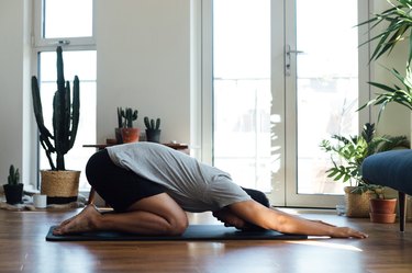 man doing yoga exercise at home on yoga mat