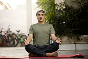 Person wearing green T-shirt and black pants doing the best yoga poses for arthritis.