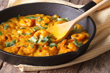 Prawns in curry sauce in a frying pan close-up. Horizontal