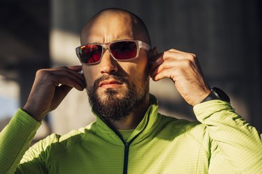 Portrait of a Handsome Bald Sportsman Putting Earphones on, Preparing for a Jog