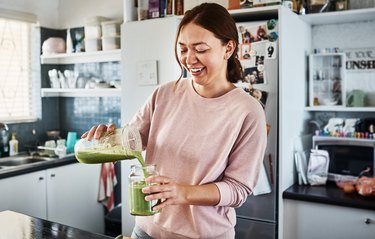a woman drinking a green smoothie with antioxidants to reduce inflammation