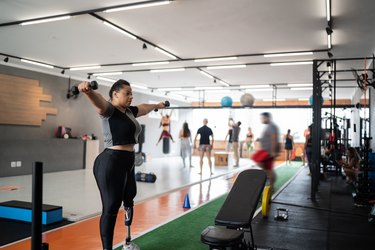 Person with prosthetic limb lifting free weights at the gym