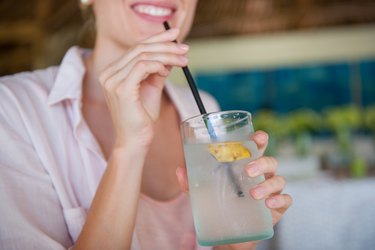 a woman drinking coconut water, as an example of a hangover electrolyte drink