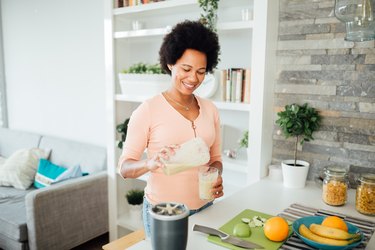 A person preparing a nutritious breakfast protein shake with protein powder and fresh fruits at home