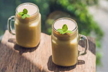 Banana smoothies and bananas on an old wooden background