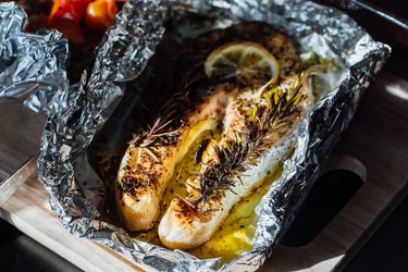 an overhead photo of a fish steak baked with lemon and herbs in foil