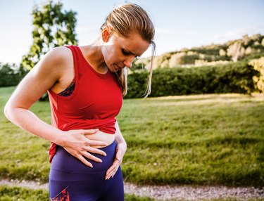 person exercising with ovarian cysts, holding their stomach in pain