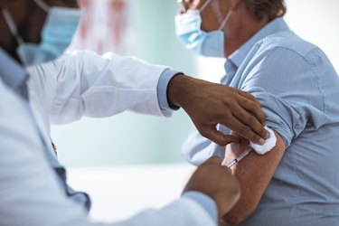 Mature man taking a COVID-19 vaccine from his doctor