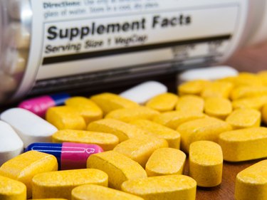 close up of yellow vitamins and other pills in front of supplement label showing most vitamins are calorie-free