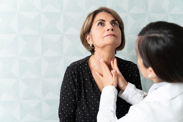 Doctor examining a patient's thyroid