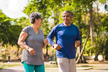 Older adult couple running at park in T-shirts