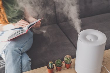 A person reading on the couch with a humidifier next to them, as a dry nose remedy