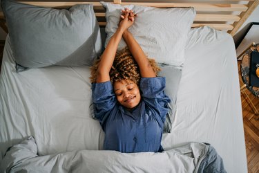 woman lying down and stretching in bed