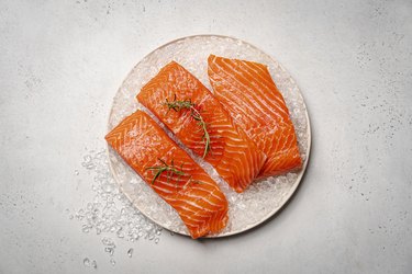 fresh raw salmon fish fillets on ice on a white plate