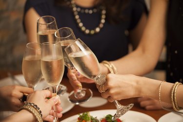 a close-up of several hands holding champagne flutes making a toast