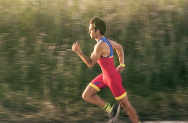 Middle-aged man in sports uniform runs alone in triathlon event. Motion blur