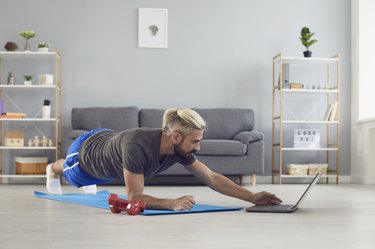 Man doing low-impact HIIT workout video in his living room on his computer