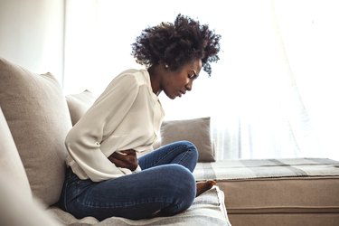 Shot of an attractive young woman suffering from stomach cramps at home.