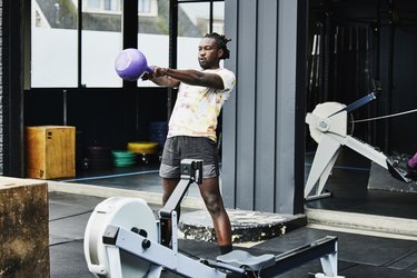Person with short dreads doing kettlebell swings while doing a metabolic workout at outdoor gym