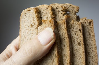 person holding slices of whole-wheat bread