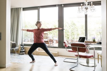 Mature woman practicing yoga in Warrior 2 pose at home