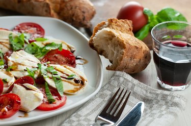 a plate with caprese salad together with bread and red wine vinegar