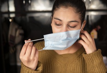 woman taking off her surgical face mask in a public place