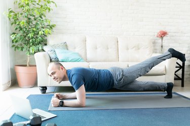 man doing plank exercises for tight hips on a blue yoga mat in his living room