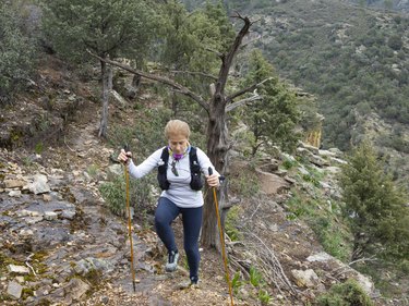 Hiker climbing up a mountain while wearing a hydration vest.