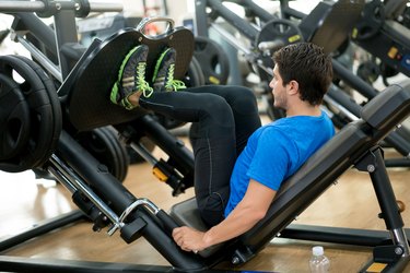 一个健康的人在健身房用腿部按压机锻炼
