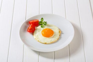 fried egg with tomatoes on white plate