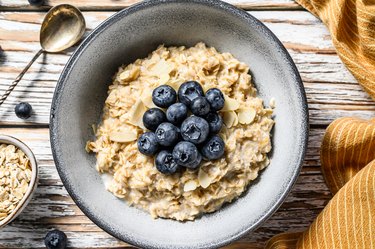 Breakfast oatmeal with  blueberries and almonds.  White wooden background. Top view