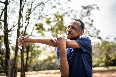 Older adult with atrial fibrillation stretching in a park