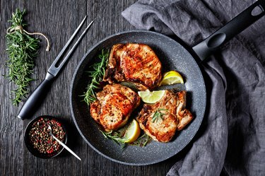 roasted pork chops with rosemary sprigs and lemon slices