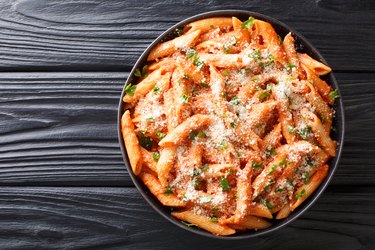 Penne alla Vodka is a classic Italian pasta dish made with penne in a creamy tomato and vodka sauce close-up in a plate. Horizontal top view