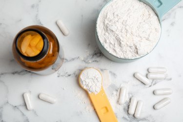 Amino acid pills and powder on white marble table, flat lay