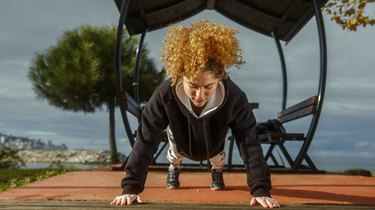 athletic woman doing push-ups outside to get rid of underarm fat