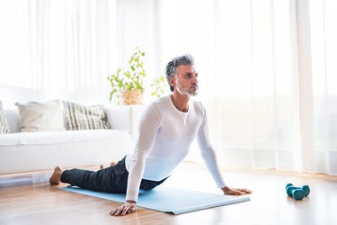 mature man doing exercise for back pain at home on mat in living room