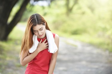 年轻漂亮的女人胸部疼痛站在模糊的背景下