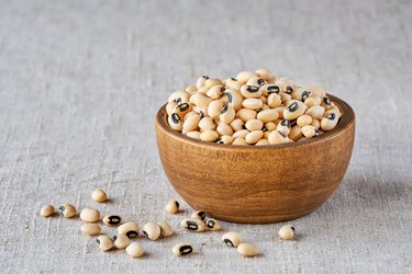 Raw black eyed pea beans in a wooden bowl on linen cloth. Closeup