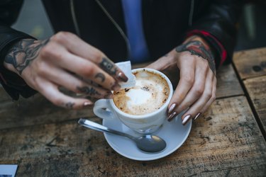 女人的手纹糖涌入一杯咖啡,特写镜头