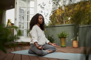 Young woman sitting in the lotus pose and doing deep breathing, as a natural remedy for nausea