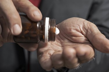 close view of a person shaking a brown bottle of pills into their hand